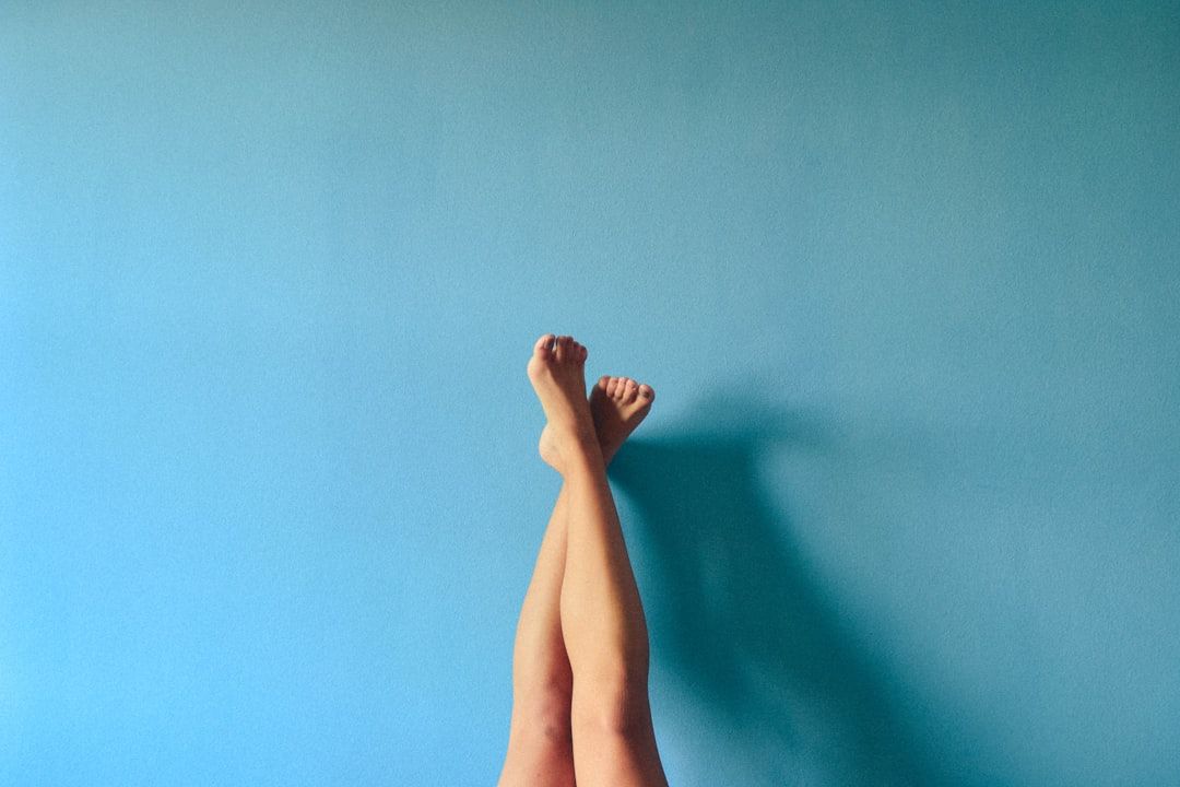 Vor einer schlichten hellblauen Wand ragen die Beine einer Person senkrecht nach oben und erinnern so an die minimalistische Kunst, die man in Aachen oft findet.