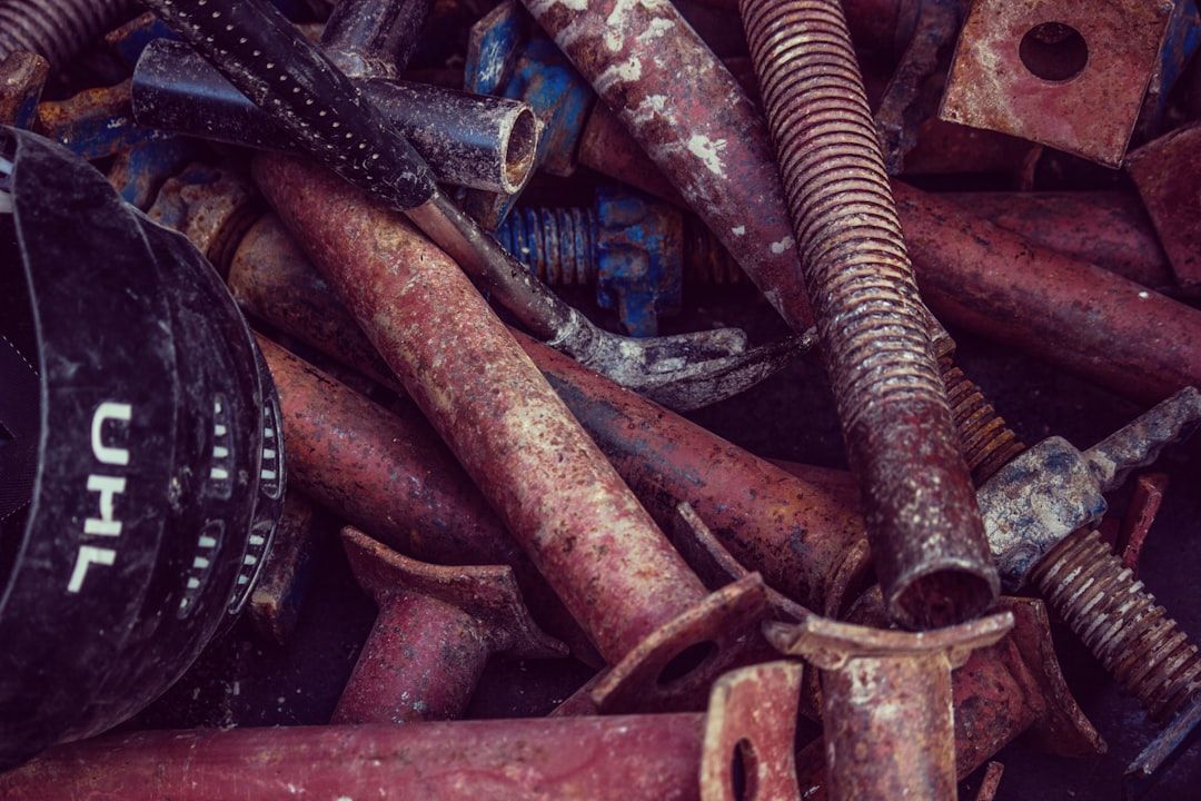 Nahaufnahme eines Haufens verrosteter, alter Metallrohre und -bolzen. Dazu ein Helm und andere Bauwerkzeuge, die an die industrielle Vergangenheit Aachens erinnern.