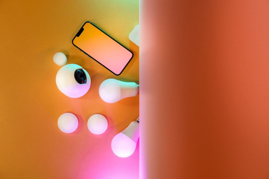 Eine Auswahl an Smart-Home-Geräten, darunter Glühbirnen, eine Smart-Kamera und ein Smartphone, ist übersichtlich auf einer gelben Oberfläche angeordnet und spiegelt ein modernes, von Aachener Innovation inspiriertes Design wider.