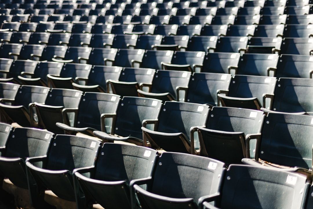 Reihen leerer, dunkelgrüner Stadionsitze, gleichmäßig angeordnet, auf die das Sonnenlicht Schatten wirft – eine Erinnerung an einen ruhigen Moment in Aachen.
