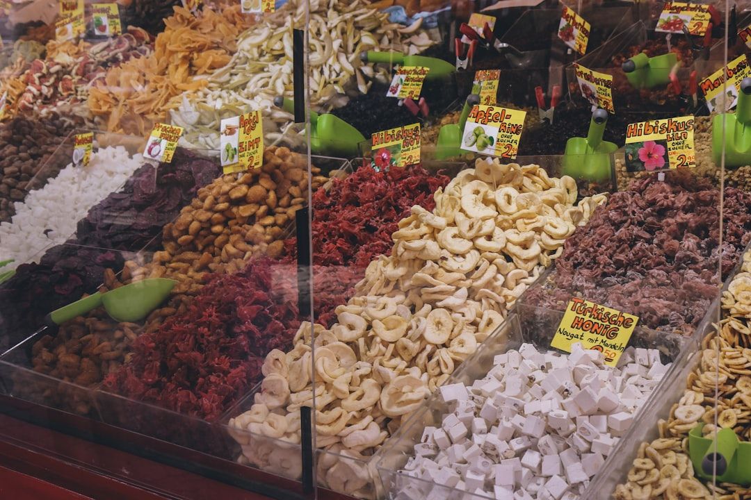 An einem Marktstand in Aachen werden verschiedene Trockenfrüchte und Nüsse mit Plastikschaufeln angeboten. Zu sehen sind diverse Schilder mit Preisen und Beschriftungen.