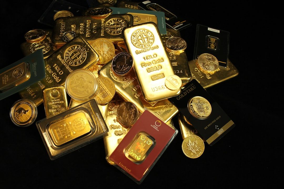 Ein Stapel verschiedener Goldbarren und Münzen aus Aachen, in unterschiedlichen Größen und Verpackungen, teils flach liegend, teils gestapelt, auf dunklem Untergrund.