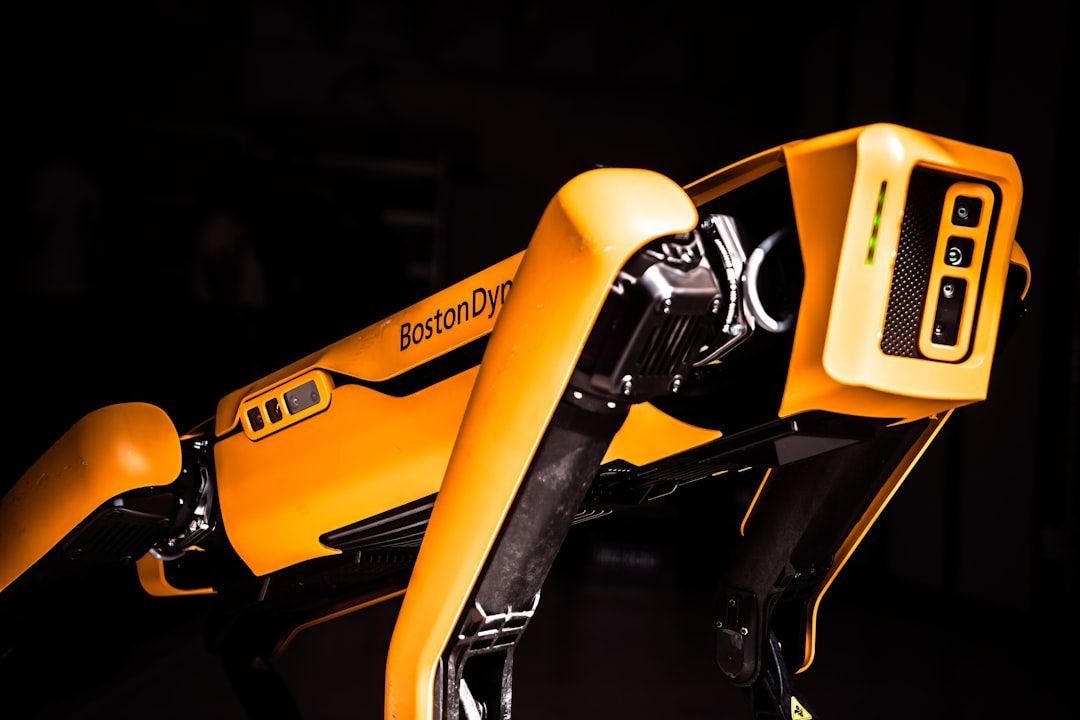 Nahaufnahme eines gelben Robotervierbeiners mit der Aufschrift „Boston Dynamics“ mit sichtbaren Gelenken und Verkabelung, der auf einer Technologieausstellung in Aachen präsentiert wurde.