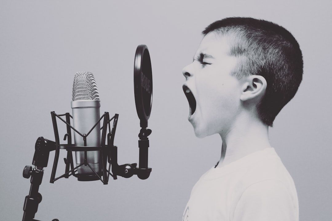 Ein kleiner Junge singt oder schreit in ein Studiomikrofon mit Pop-Filter in einem Aachener Aufnahmestudio vor einem schlichten Hintergrund.