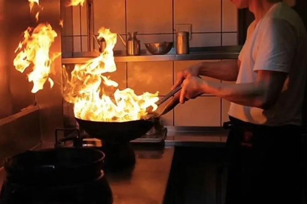 Koch am Wok mit hoher Flamme