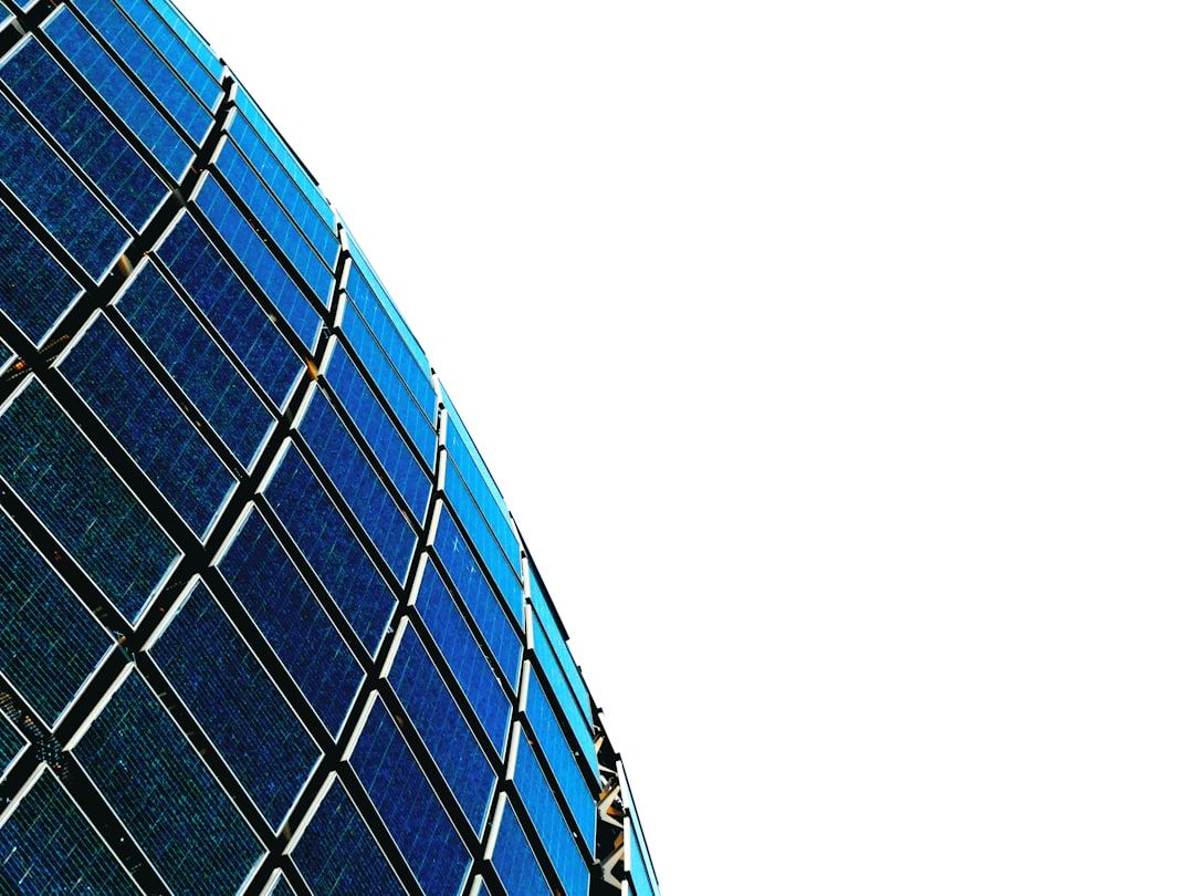 Eine Nahaufnahme einer gebogenen Anordnung blauer Solarmodule vor einem strahlend weißen Hintergrund, inspiriert von den innovativen Technologien, die in Aachen entwickelt wurden.